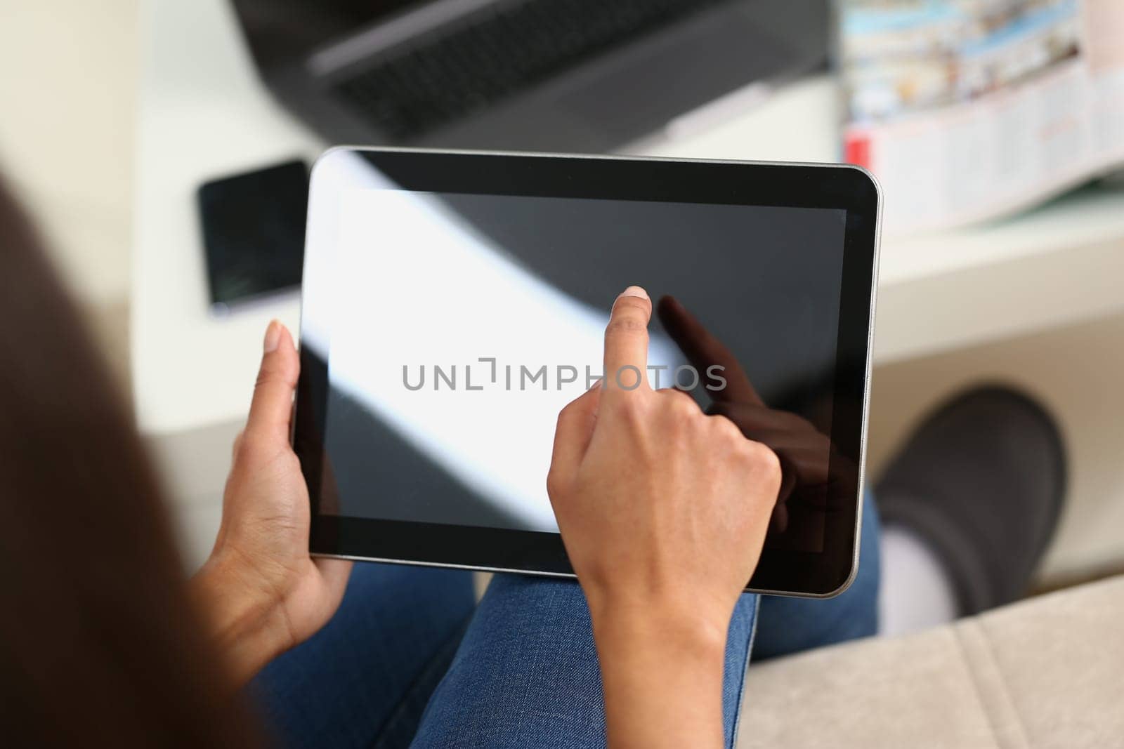Woman hand holds tablet at home and controls finger across screen. Woman surfing internet using an app
