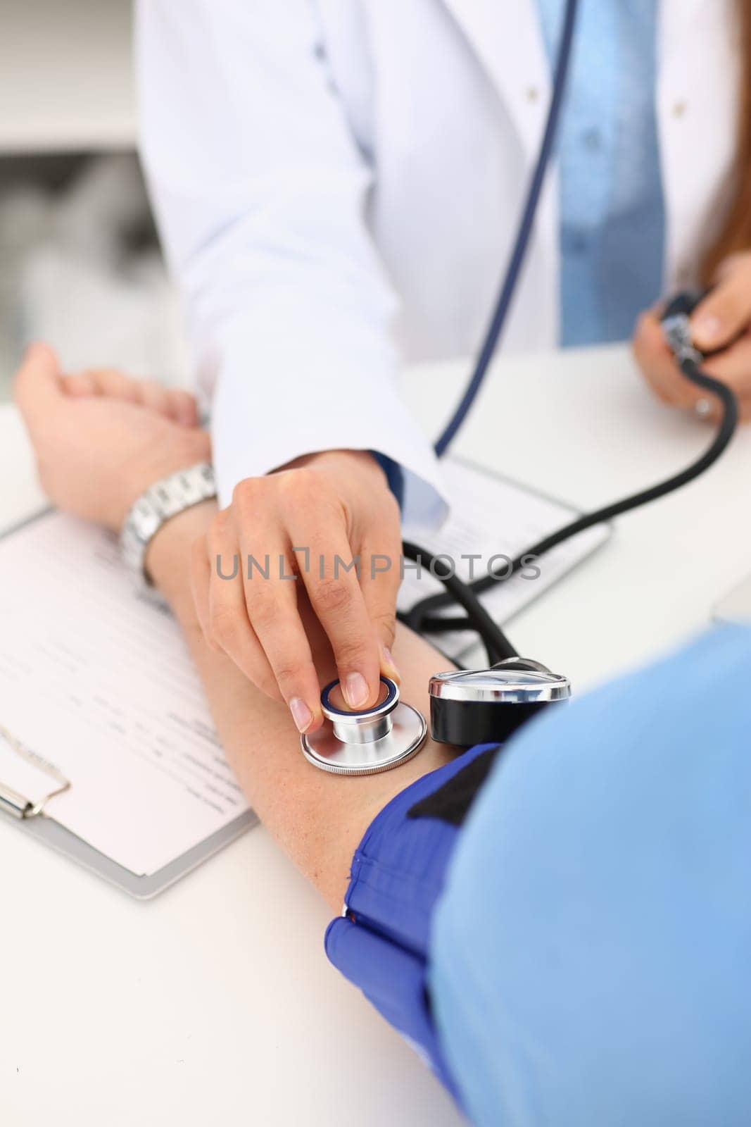 Cardiologist doctor measures blood pressure to patient with tonometer in clinic. Diagnosis of arterial hypertension and problems with pressure