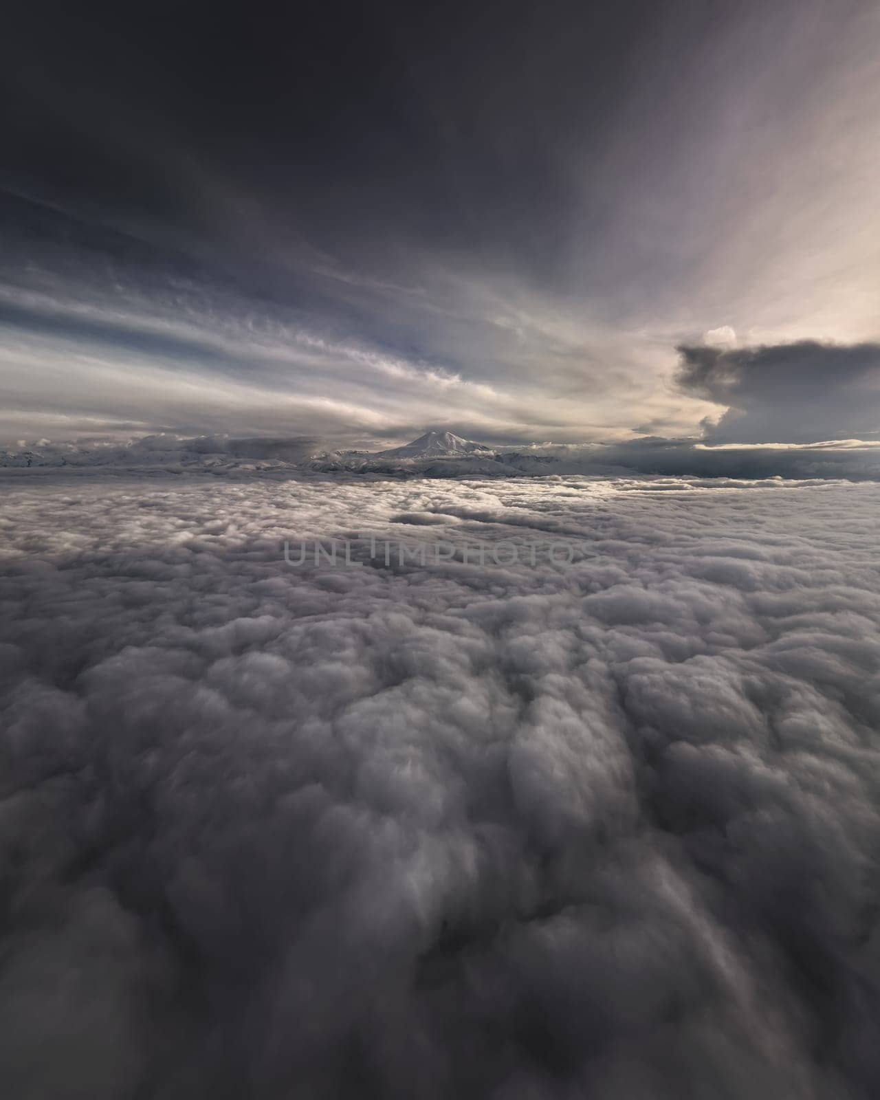 Mountains in the clouds at sunrise or sunset in summer. Aerial view of a mountain peak in the fog. Beautiful landscape. Top view from a drone on a mountain valley in low clouds. misty hills by yanik88