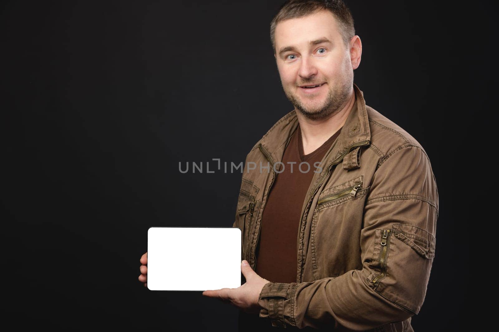 man holds an electronic tablet with a blank screen in his hands, smiles. handsome man showing blank screen of digital tablet isolated on white background by yanik88