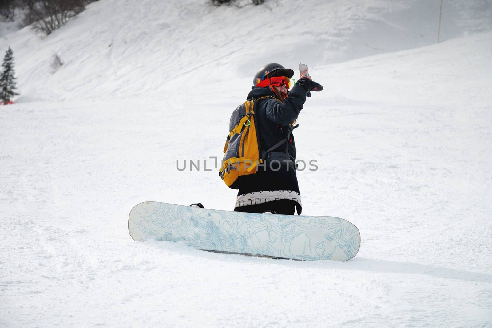 snowboarder sits on a mountain and takes pictures. Winter landscape in the French Alps. beautiful woman in snowboarding clothes sitting on snowboard track by yanik88