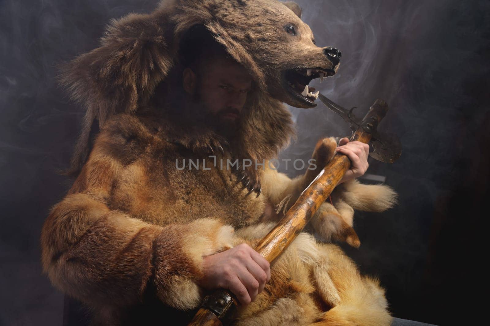 A man with a bear's head, clothes made from the skin of an animal. Warrior cosplay costume.