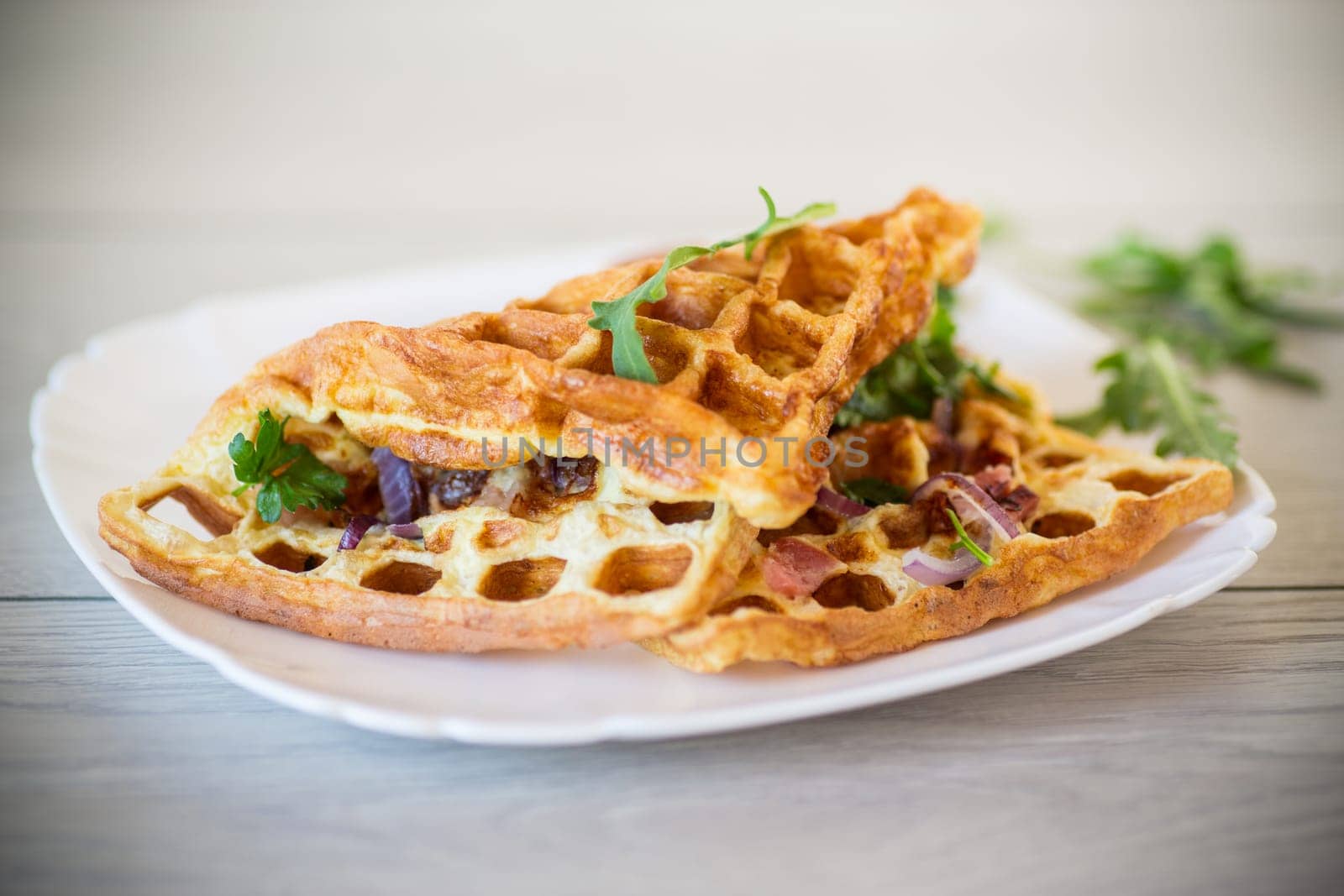 Egg omelette stuffed with onions and herbs, fried in the form of waffles, on a wooden table