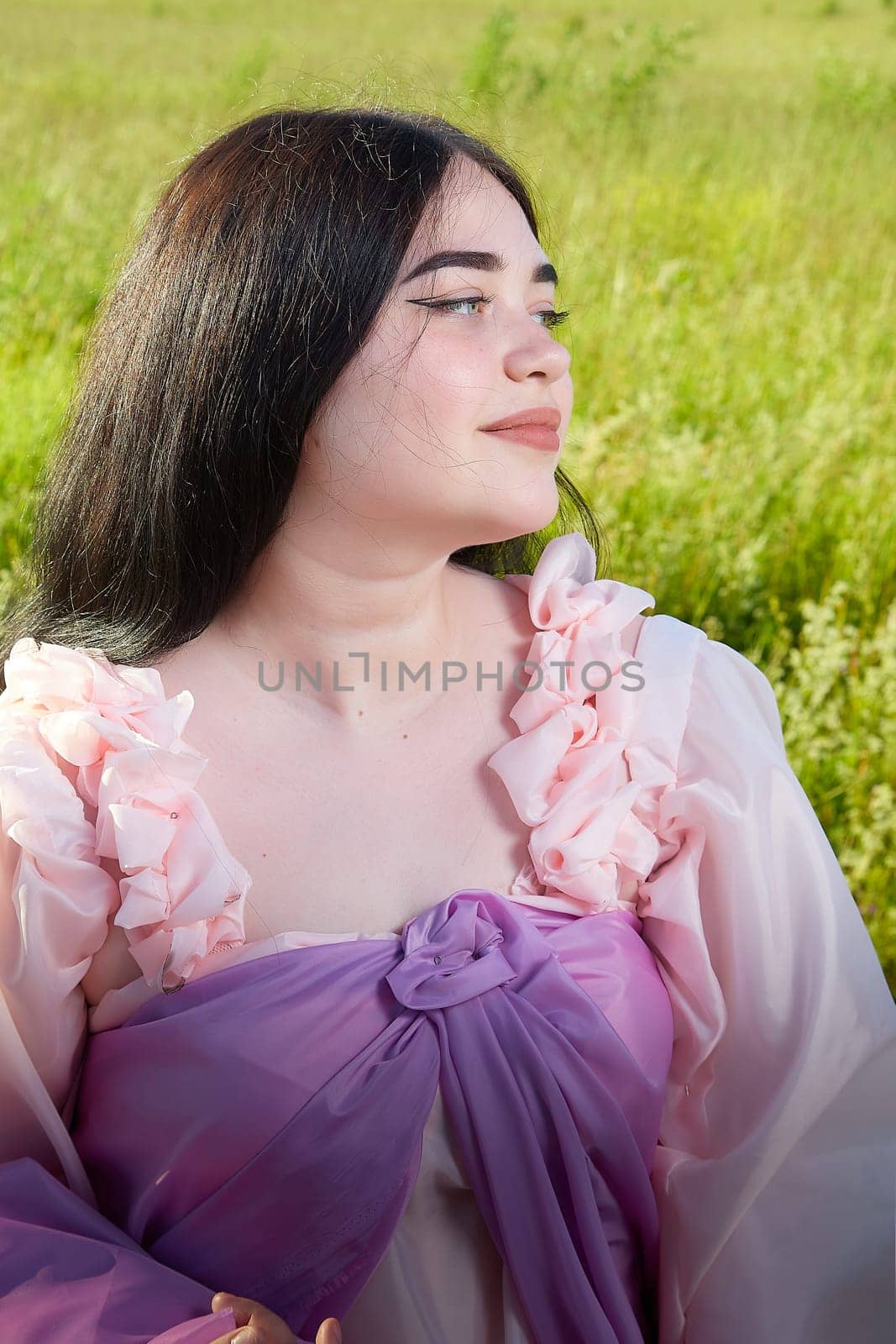 Young plump curvy beautiful teenage girl in a field or meadow on sunny summer day in the evening sunset sun. Plump black-haired and black-eyed oriental model from the east fairy tale