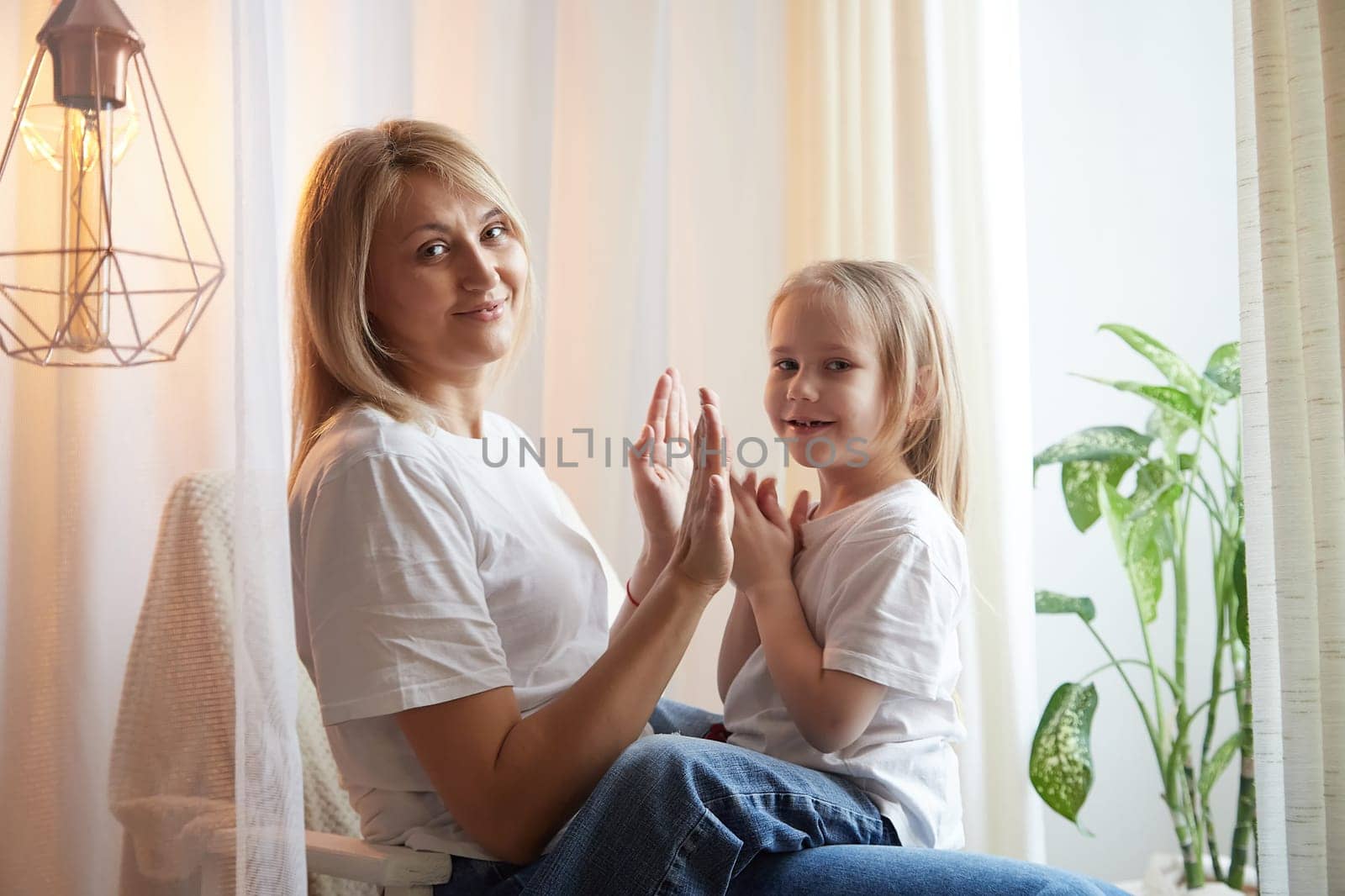Happy loving family with mother and daughter in living room. Woman mom and small child girl playing and having convercation inside of home