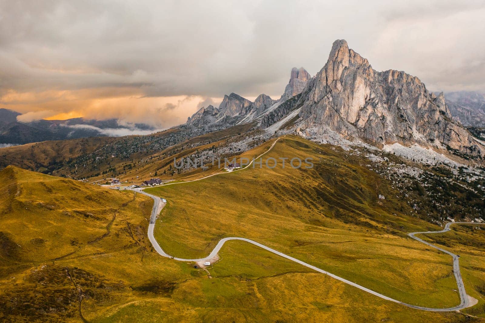 Pathway from Snake Road to high mountain range illuminated by bright sunlight. Small mountain resort for tourists located in Giau Pass