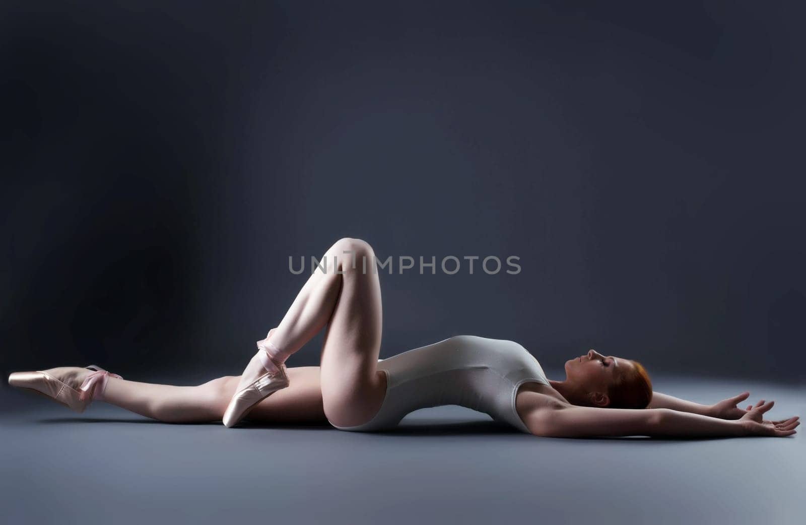 Image of gorgeous slender ballerina laying in studio, close-up
