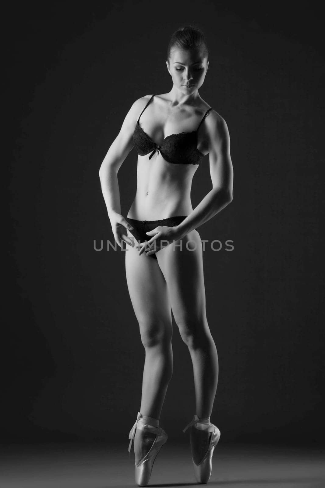 Black and white image of graceful slim ballerina posing in studio
