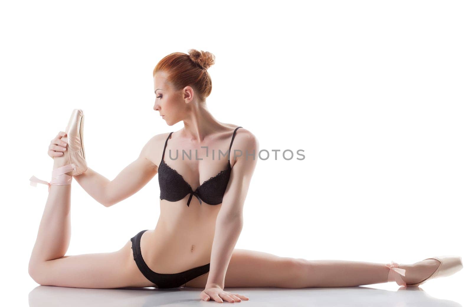 Flexible young girl posing in lingerie and pointes, isolated on white