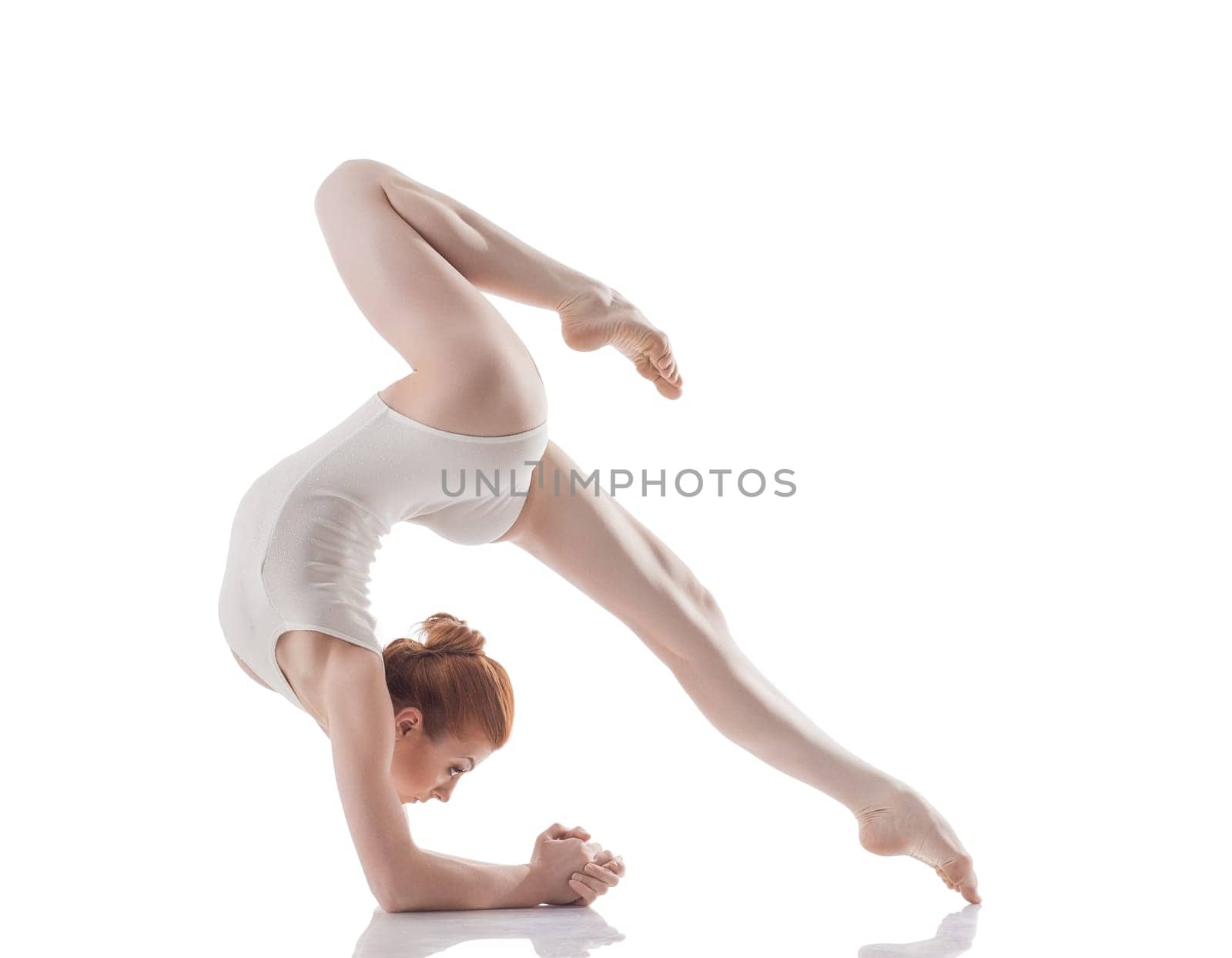 Attractive slim girl doing acrobatic trick, isolated on white