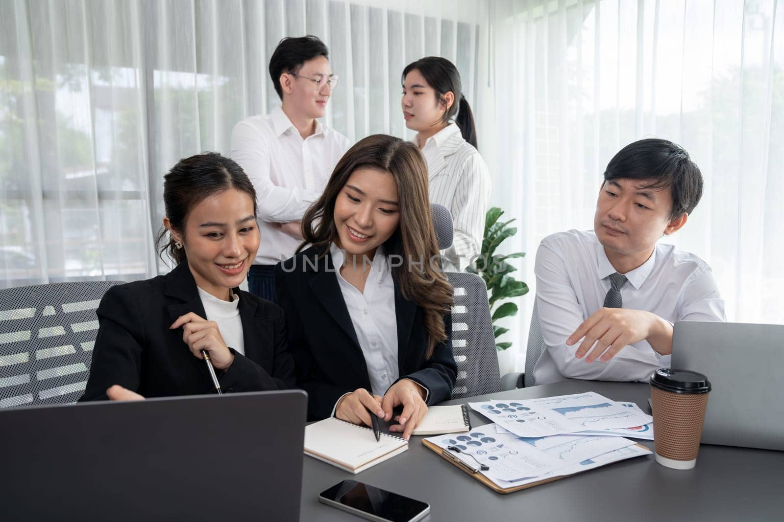 Harmony in office concept as business people analyzing dashboard paper together in workplace. Young colleagues give ideas at manager desk for discussion or strategy planning about project.