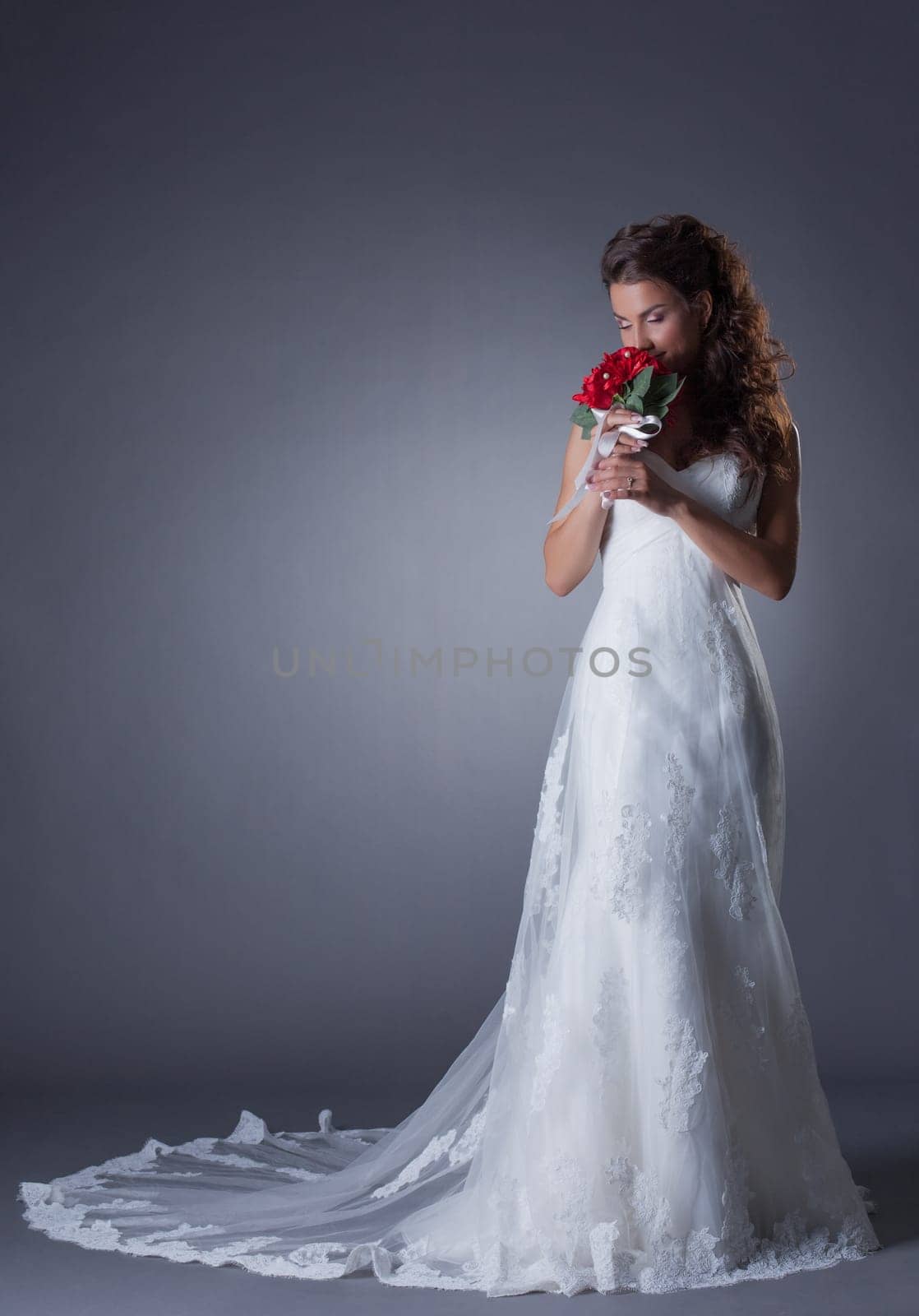 Happy bride posing in chic trendy dress, on gray background