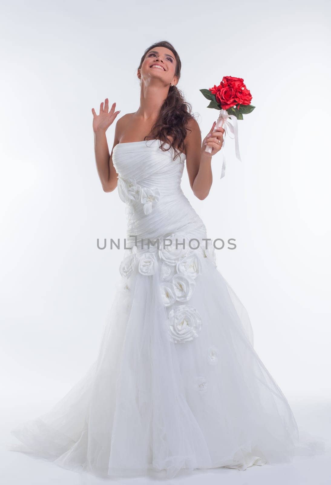 Cheerful young bride posing with bouquet of red flowers