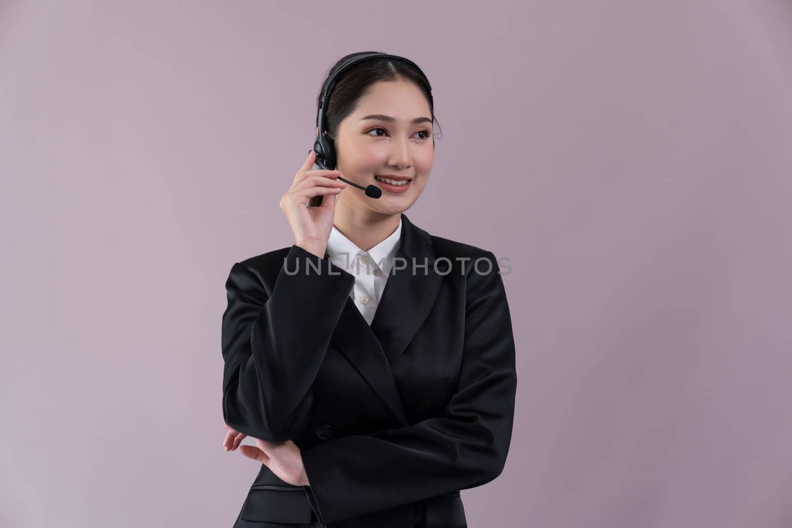 Attractive asian female call center operator with happy smile face advertises job opportunity on empty space, wearing a formal suit and headset on customizable isolated background. Enthusiastic