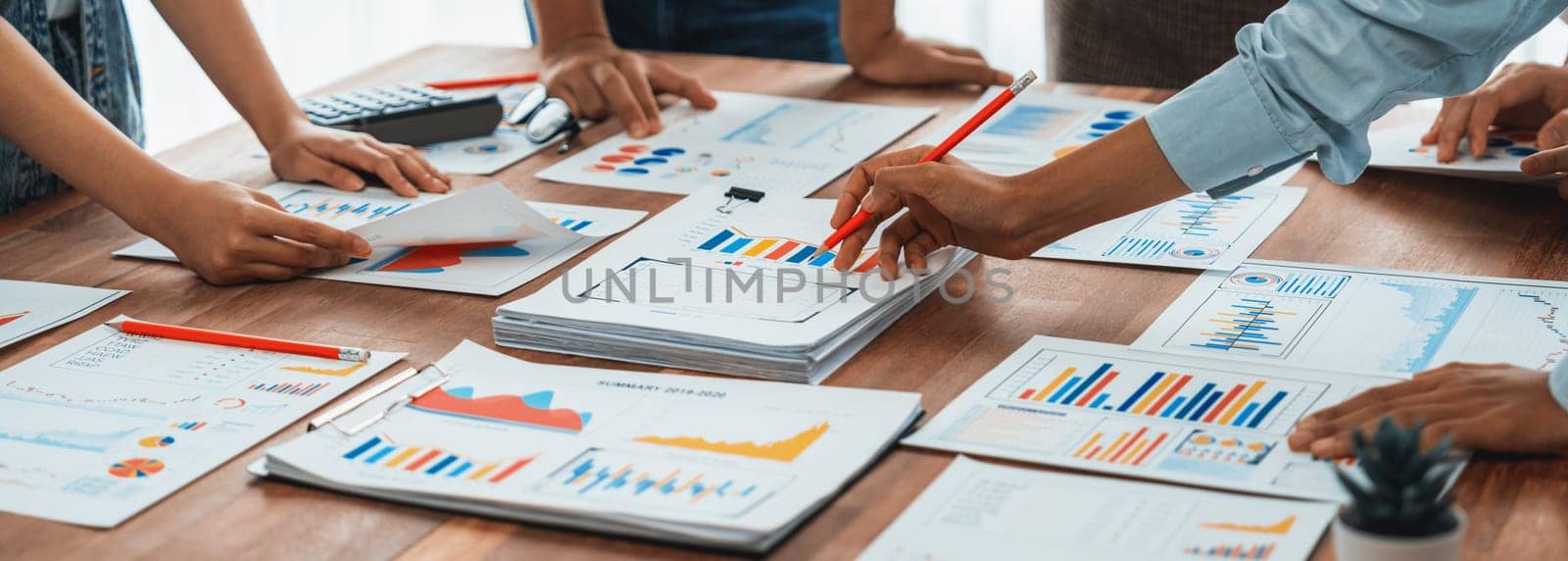 Analyst team utilizing BI Fintech to analyze and pointing at financial dashboard paper office. Businesspeople examining report paper on table for business insight. Panorama shot. Scrutinize