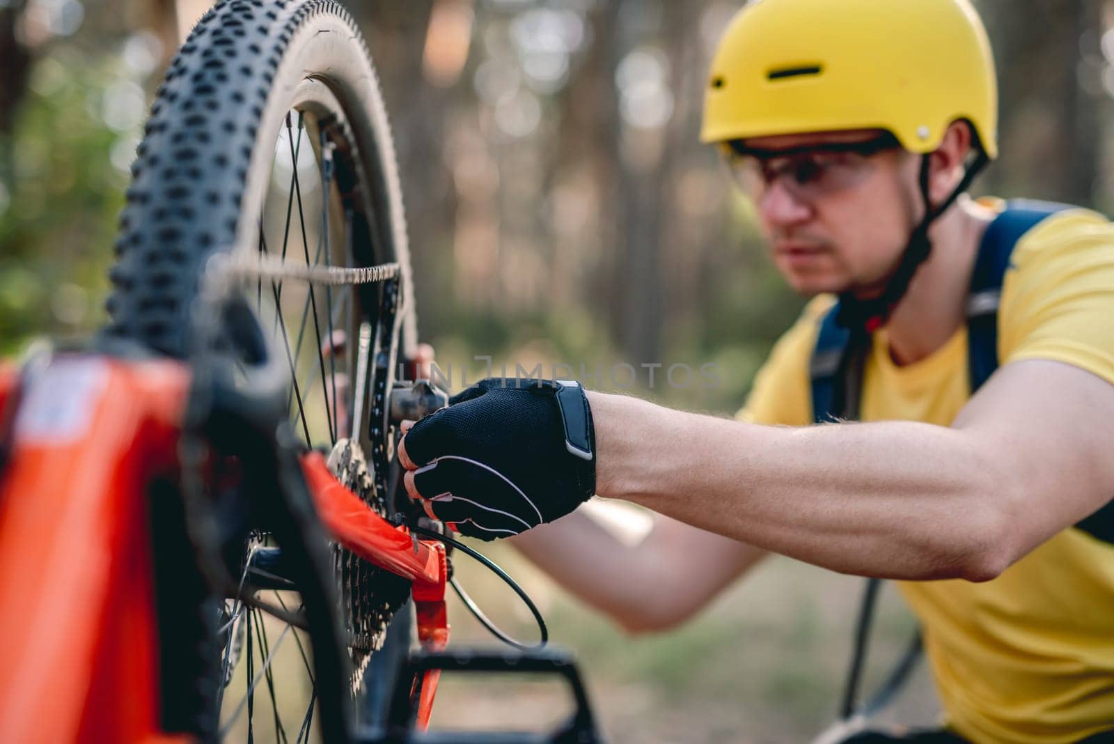 Cyclist checking chainwheel defect on upside down bicycle in forest