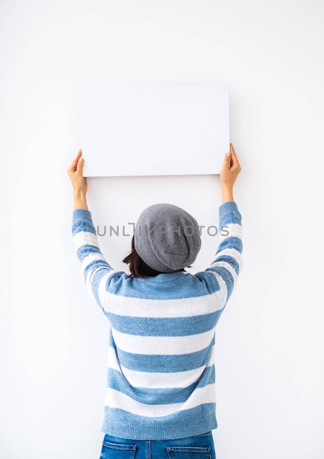Girl holding blank canvas on white wall