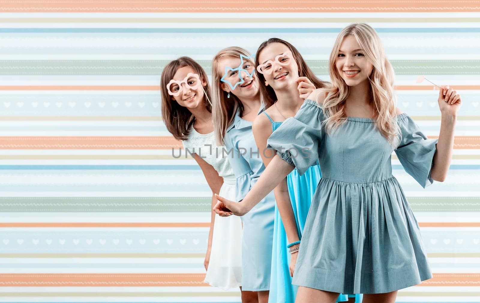 Smiling teenage girls posing emotionally on striped background