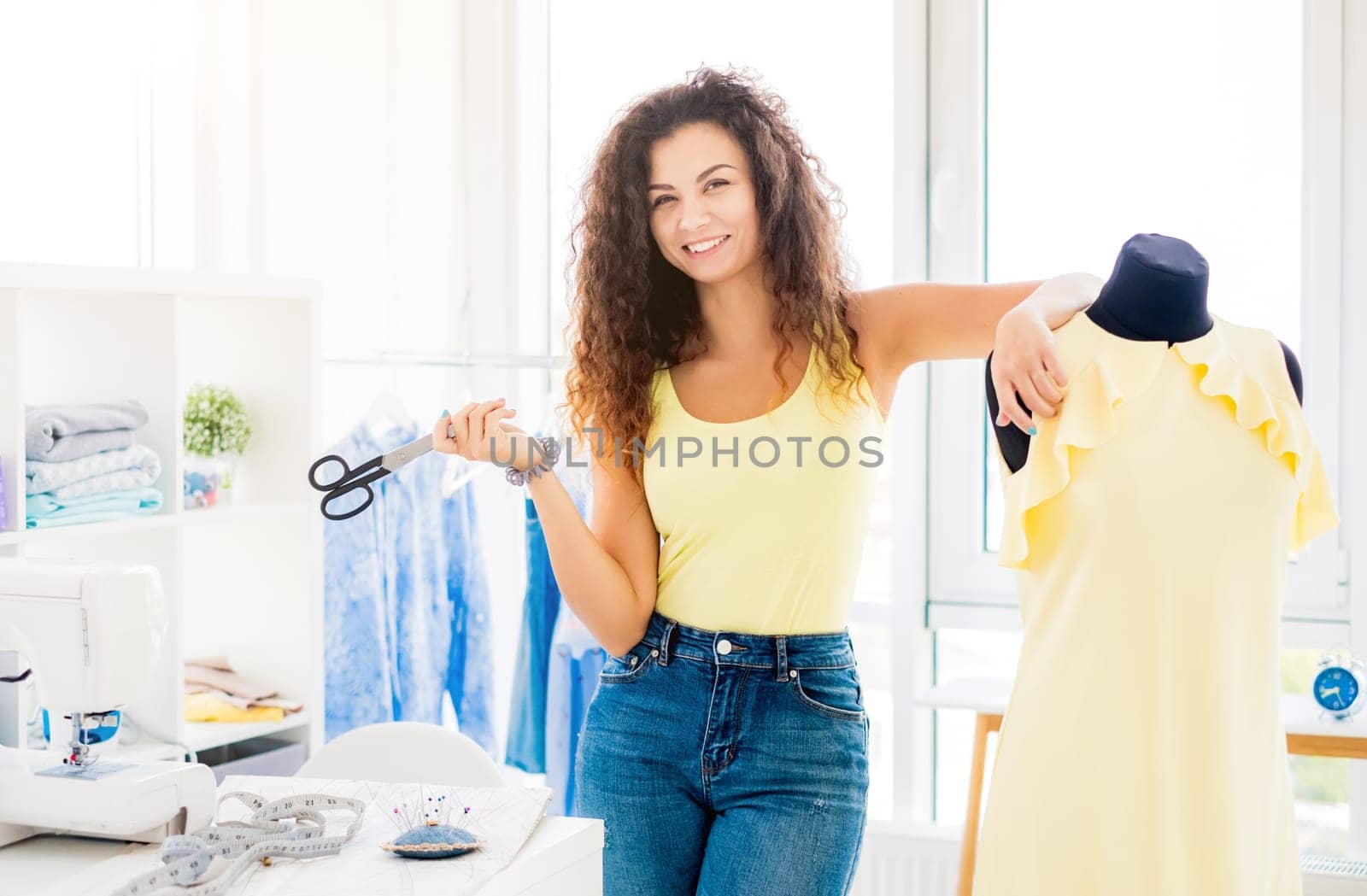 Young cute designer with finished dress on mannequin