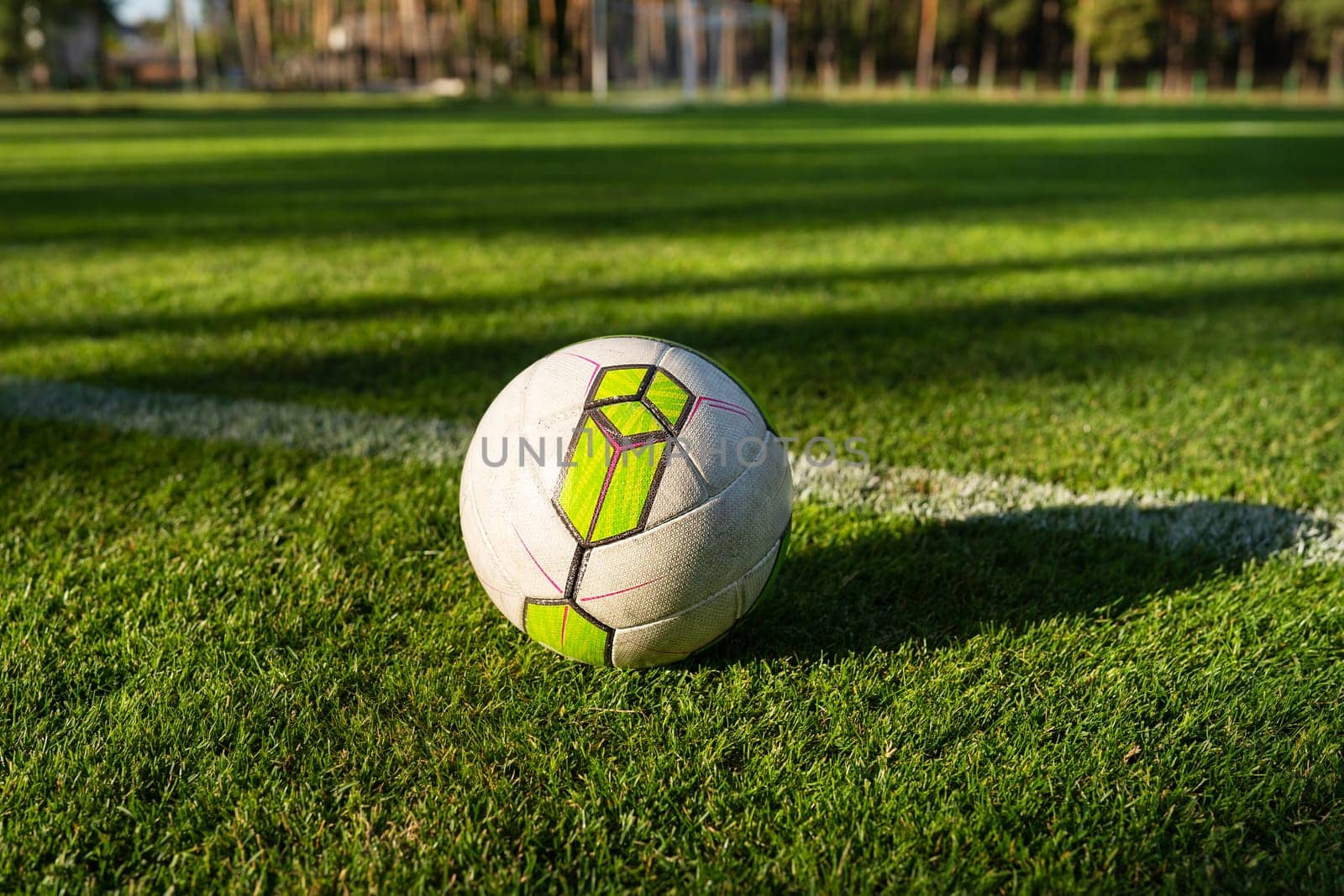 A ball on a freshly mown field, close-up. Local football. Soccer grass field near a pine forest, training in the fresh air