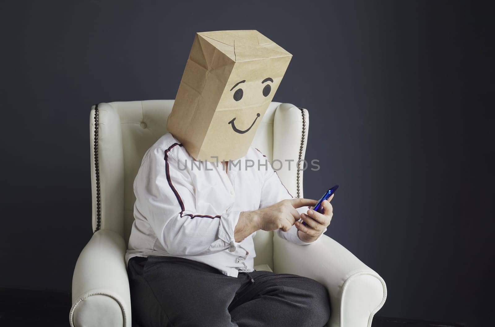 A man in a white shirt with a paper bag on his head, with a smiley face drawn, is typing a message on a smartphone by Sd28DimoN_1976