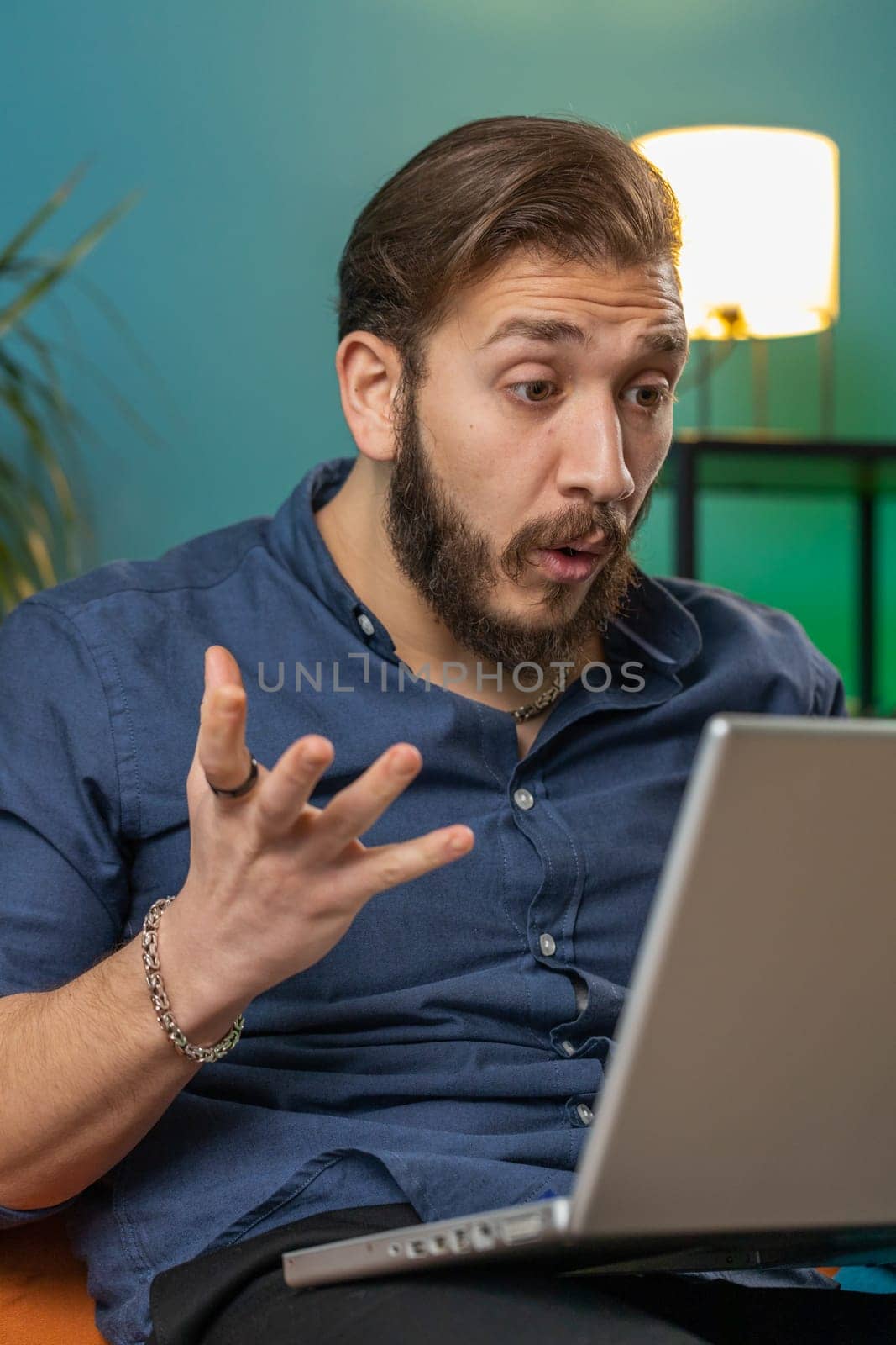 Surprised lebanese man guy using laptop computer receive mail good news message, shocked by sudden victory celebrate lottery jackpot win purchases online shopping at home apartment on sofa. Lifestyles