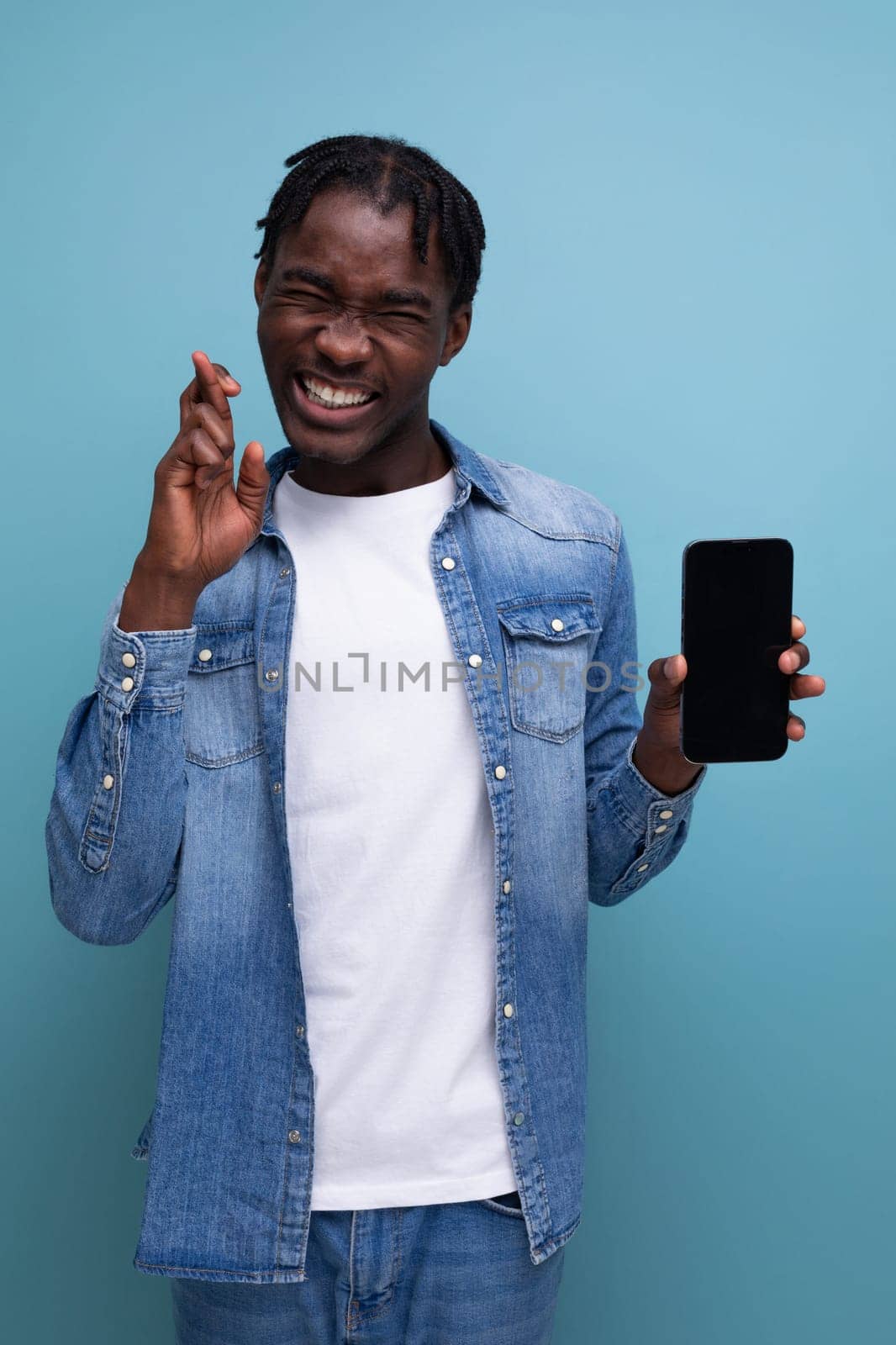 smiling african man with black dreadlocks using smartphone.