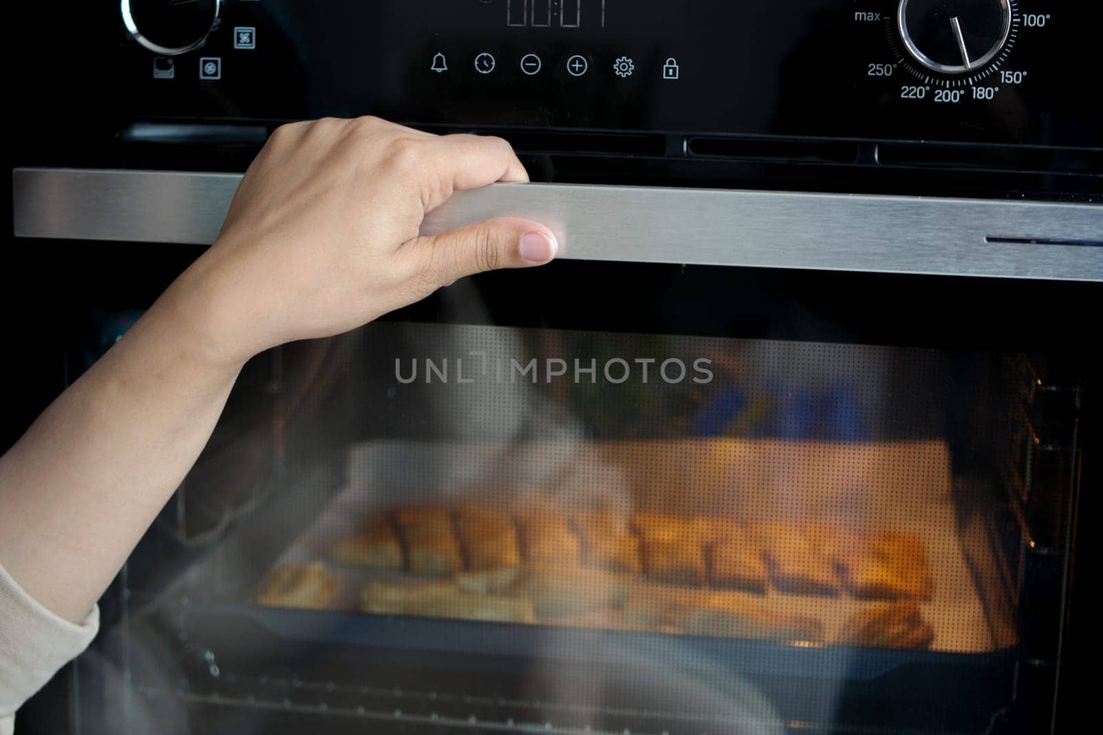 Cropped view of hand open door at silver gas oven.