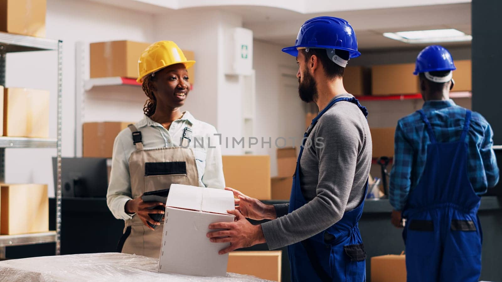 Diverse employee checking list on digital tablet, looking at warehouse products packages to ship depot goods. Man and woman scanning barcodes for logistics, industrial cargo. Handheld shot.