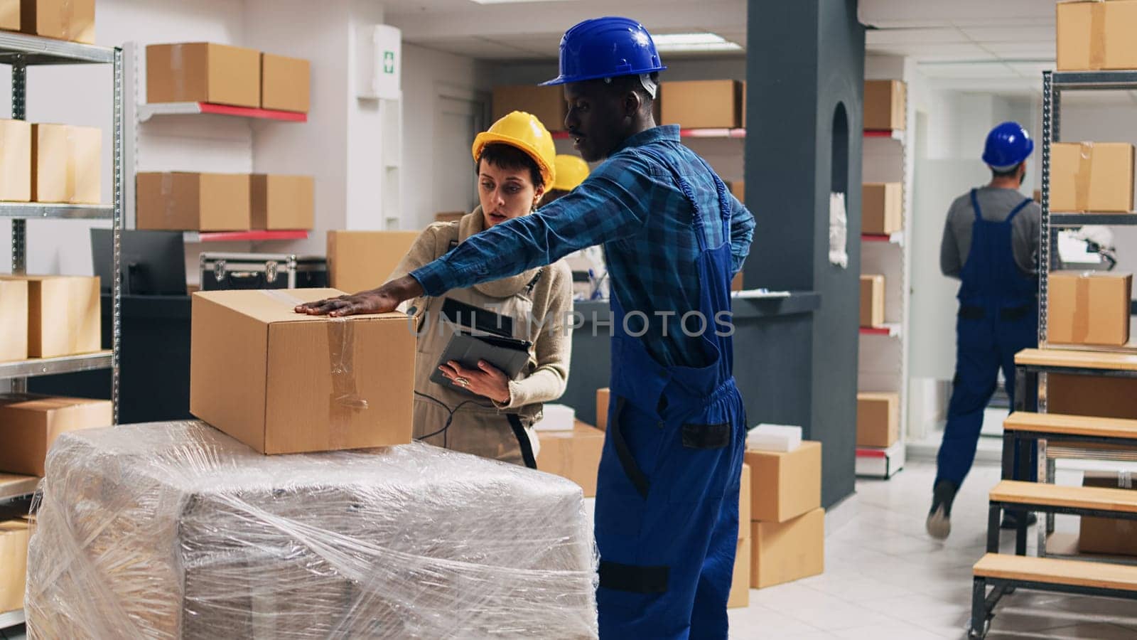 African american man bringing box of goods to manager to scan barcodes and plan inventory for merchandise on racks. Team of people doing quality control with scanner and digital tablet.