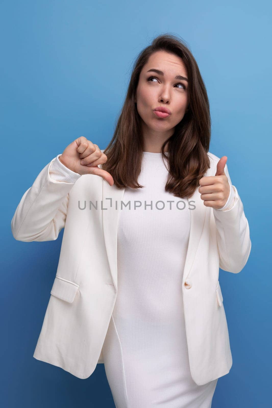 surprised young brunette woman in white dress pointing her finger to the side.