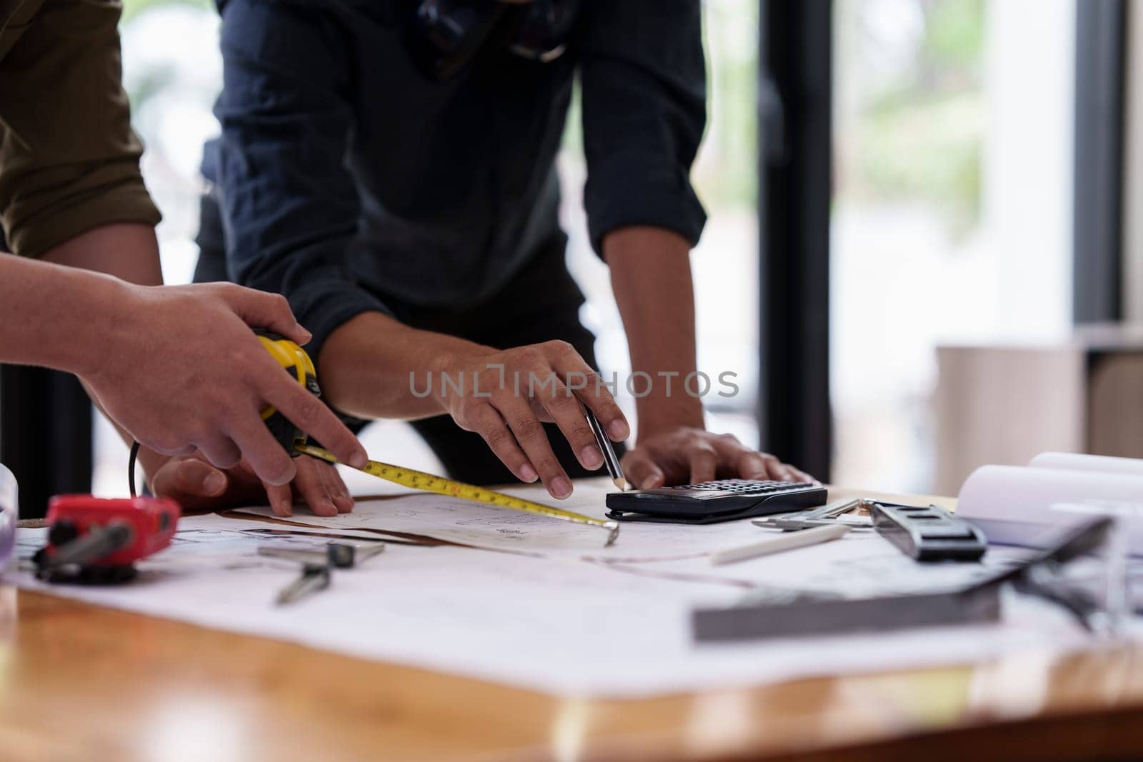 Architect and Engineer working with blueprints for architectural plan, engineer sketching a construction project, green energy concept.