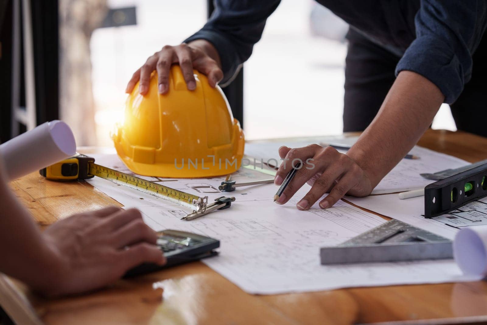 Architect and Engineer working with blueprints for architectural plan, engineer sketching a construction project, green energy concept.