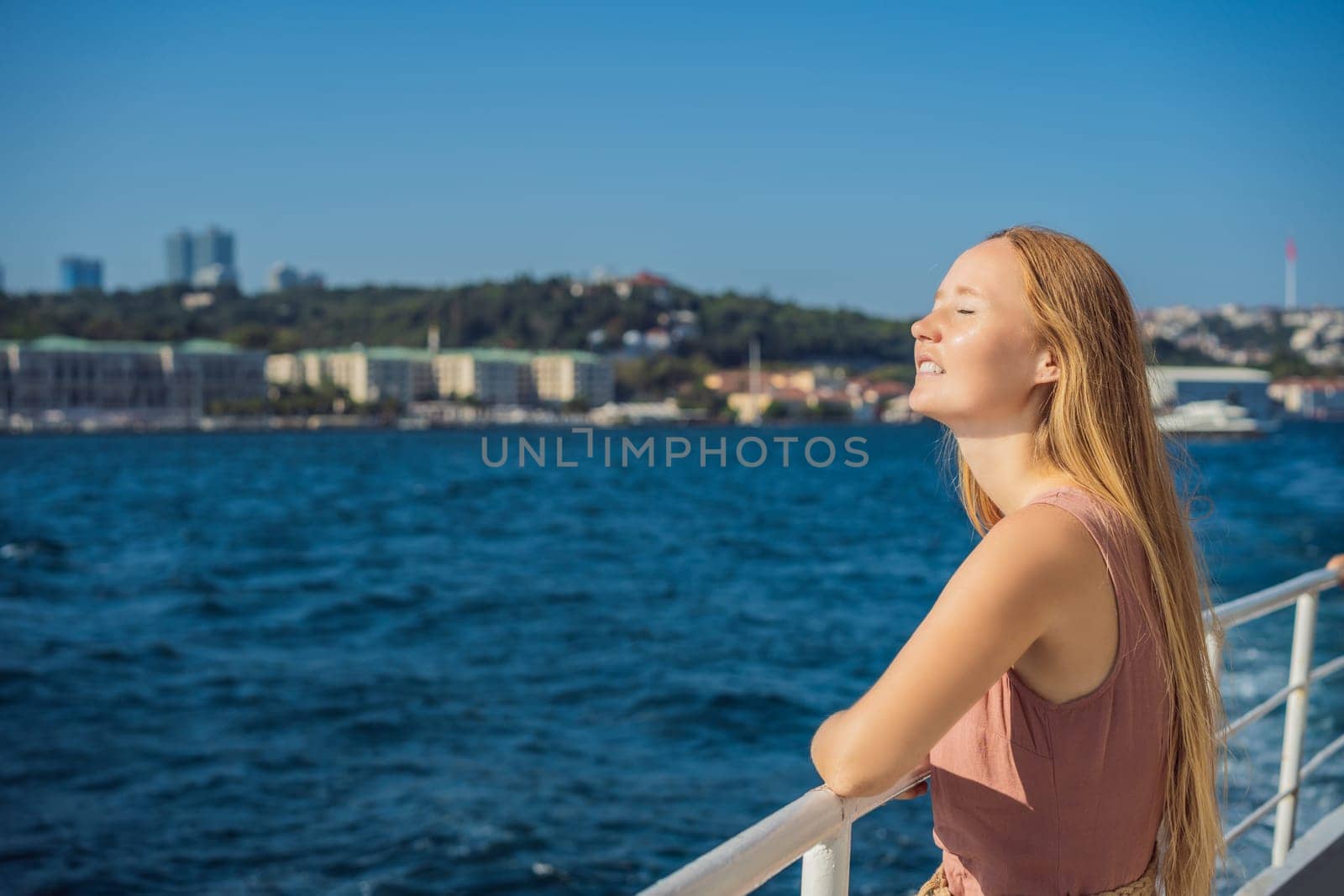 Happy woman enjoying the sea from ferry boat crossing Bosphorus in Istanbul. Summer trip to Istanbul.