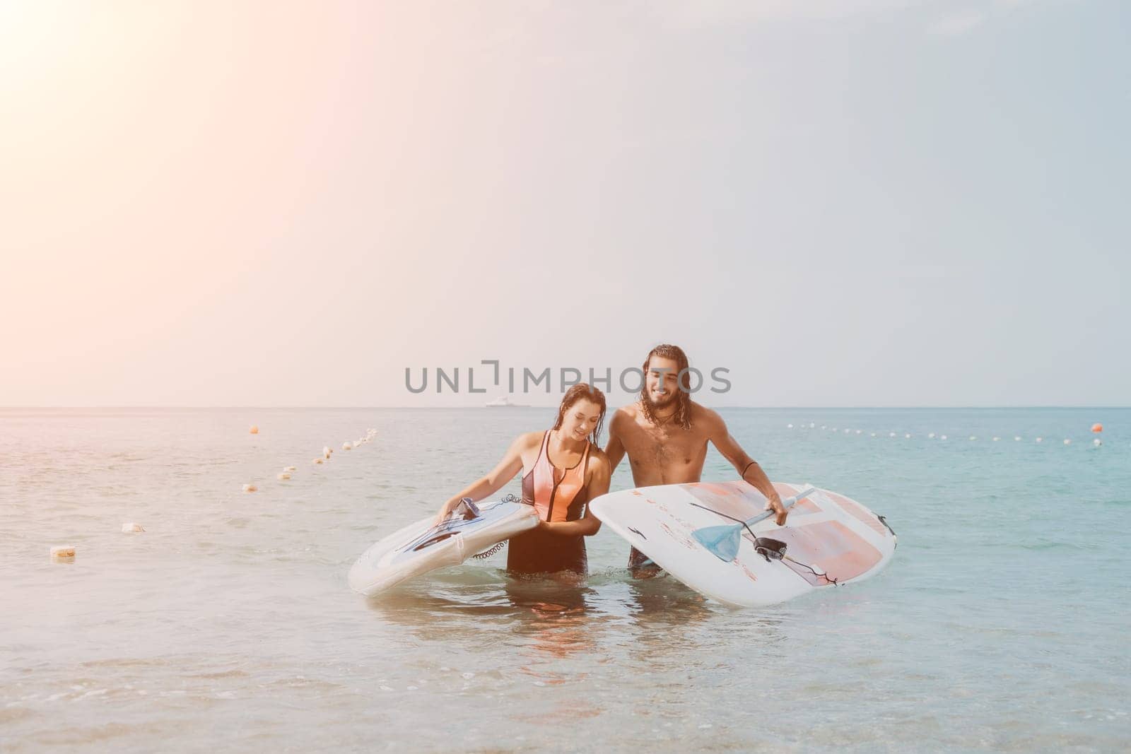 Woman man sea sup. Close up portrait of beautiful young caucasian woman with black hair and freckles looking at camera and smiling. Cute woman portrait in a pink bikini posing on sup board in the sea