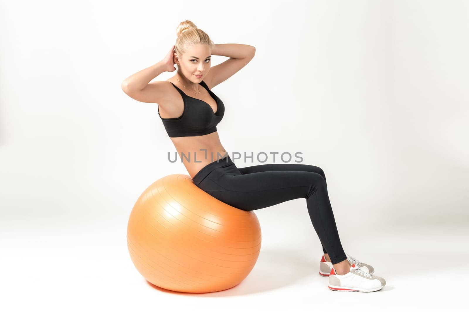 Young blonde woman training with fitball. Fitness exercises for abdomen. she looks into the camera