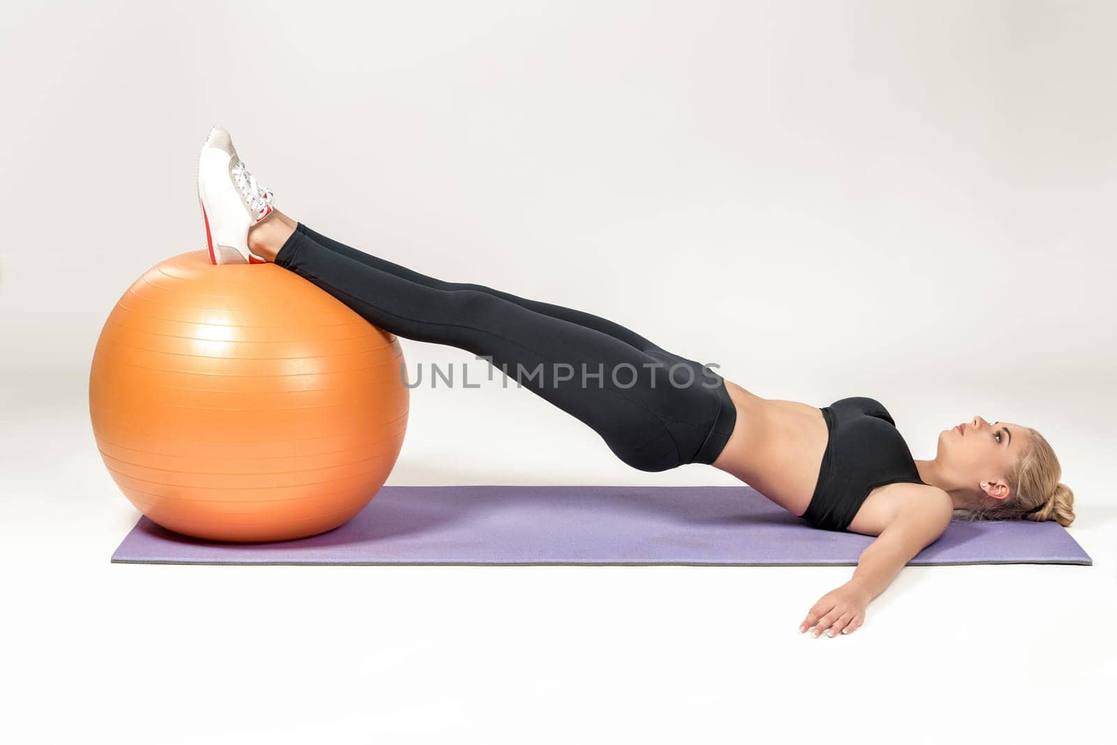 Young blonde woman training with fitball on the mat. Fitness exercises