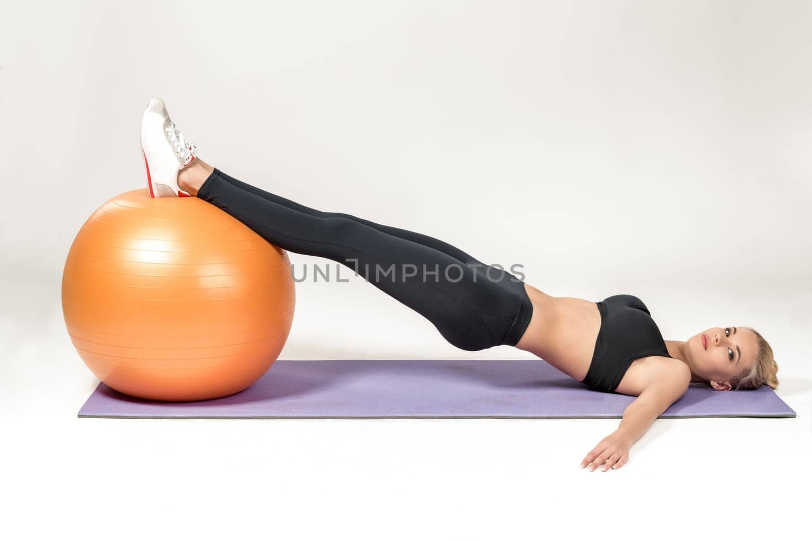 Young blonde woman training with fitball on the mat. Fitness exercises