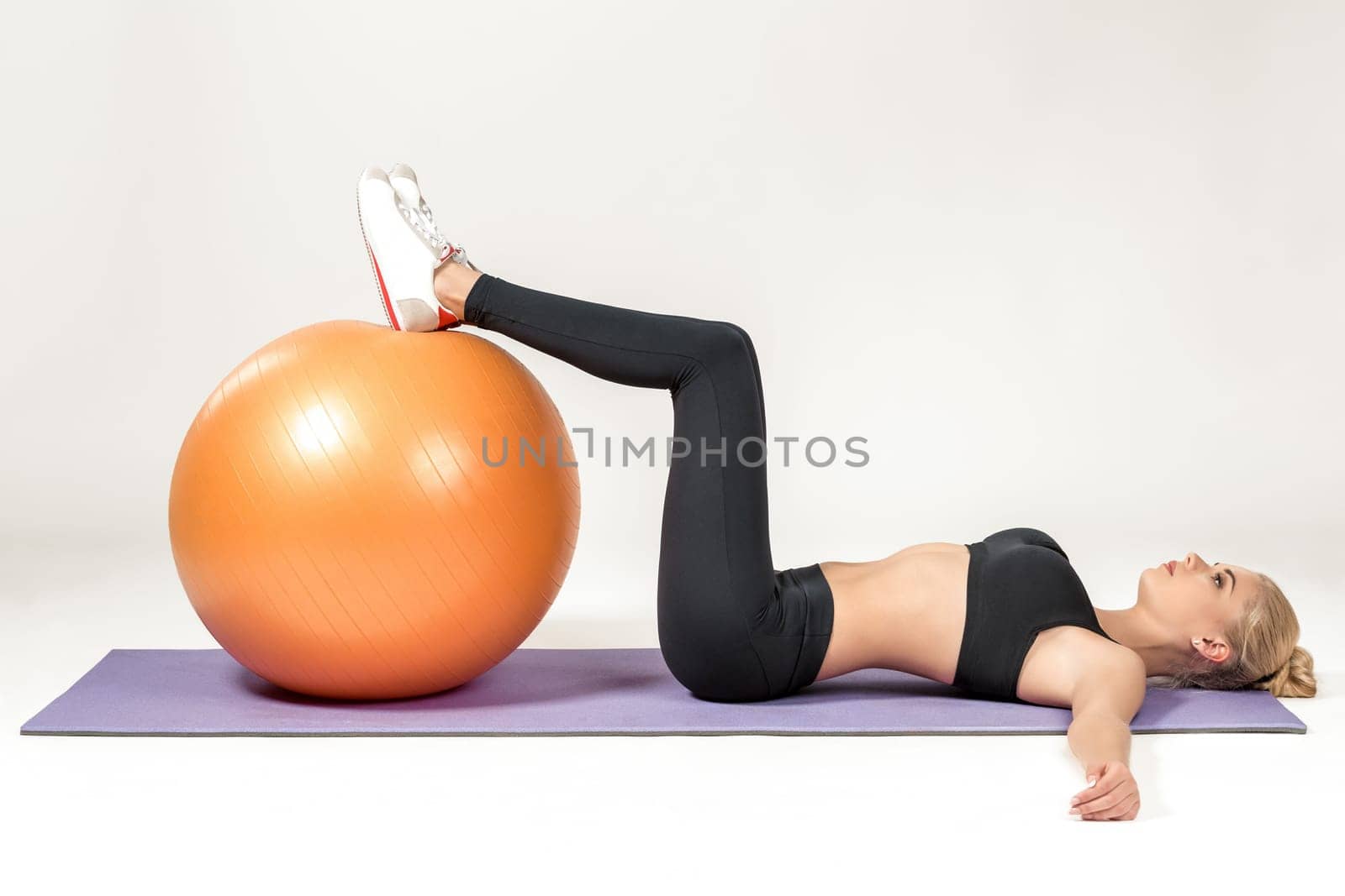 Young blonde woman training with fitball on the mat. Fitness exercises