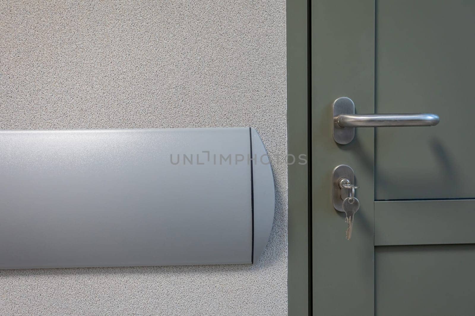 Fragment of a door with a handle and an insert and hanging key in a newly completed room for use. Plastic bumper mounted wall.