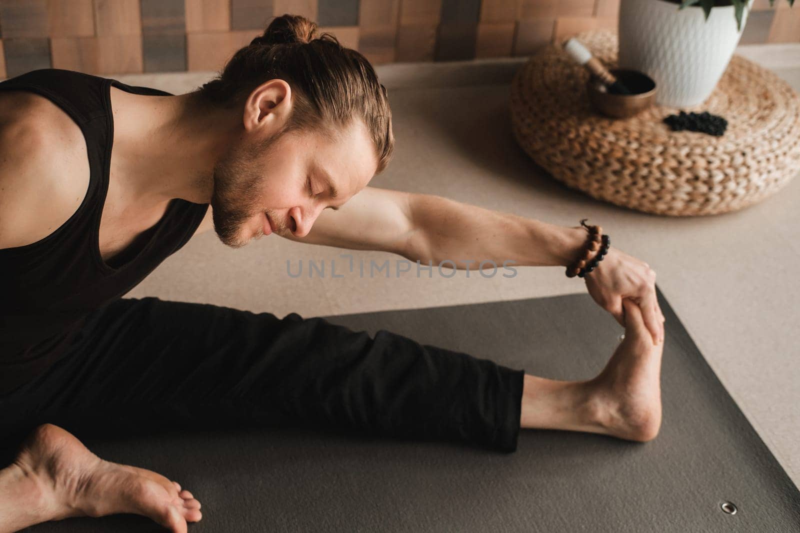 A man performing gymnastic exercises on a yoga mat at home by Lobachad