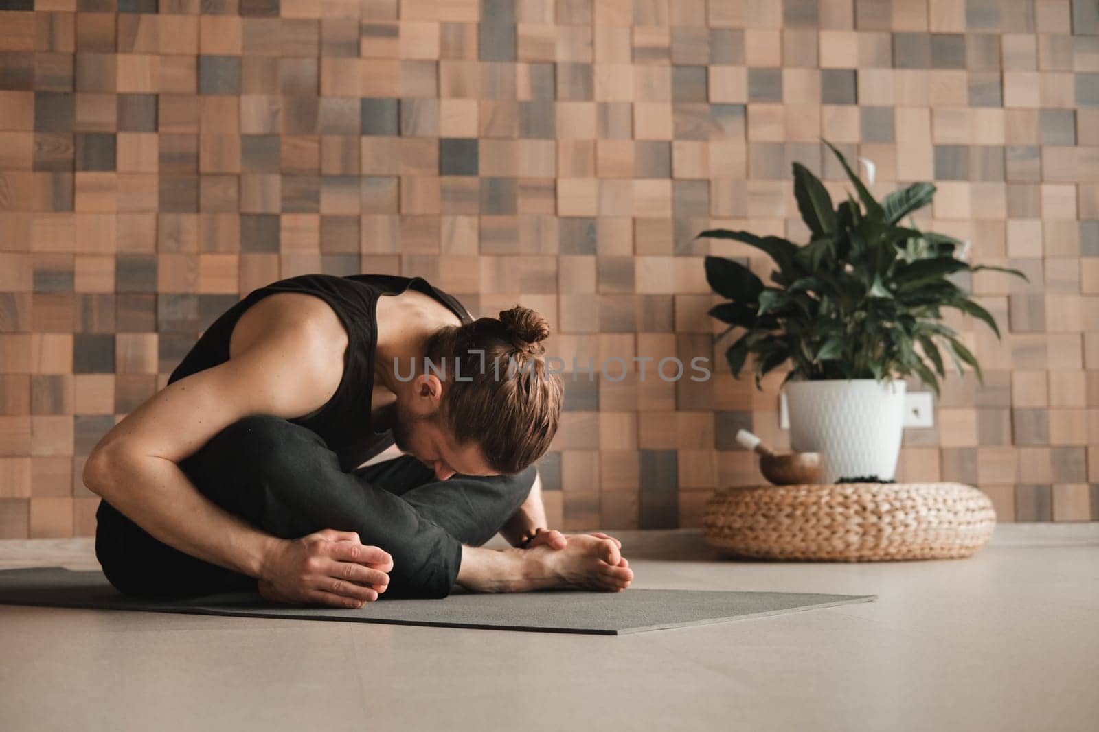 A man performing gymnastic exercises on a yoga mat at home by Lobachad