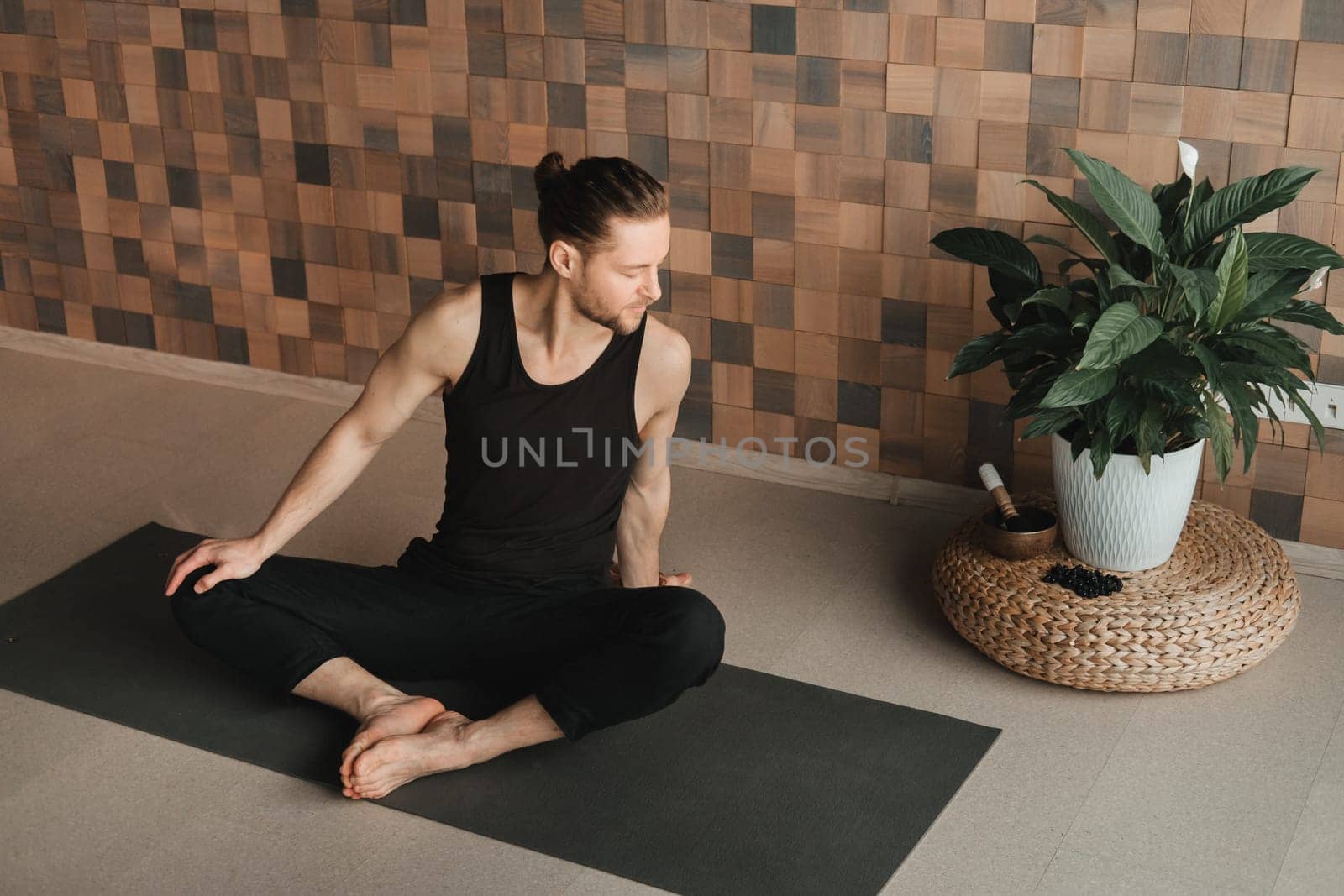 A man performing gymnastic exercises on a yoga mat at home by Lobachad