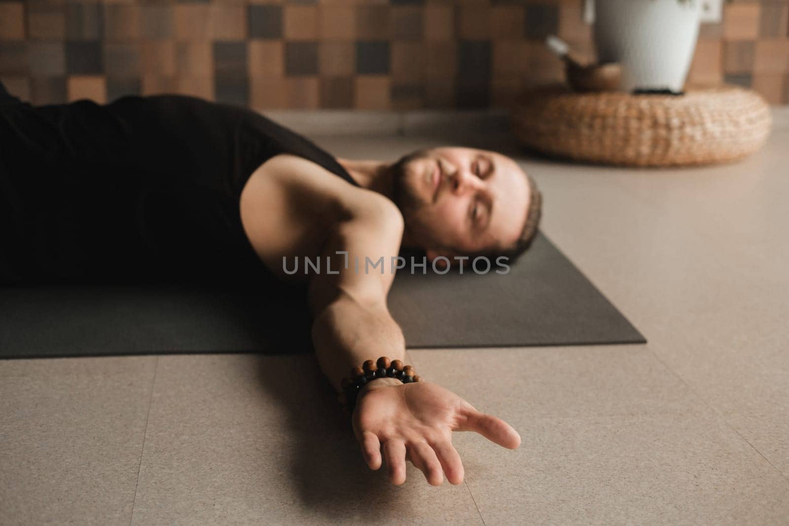 A man performing gymnastic exercises on a yoga mat at home by Lobachad