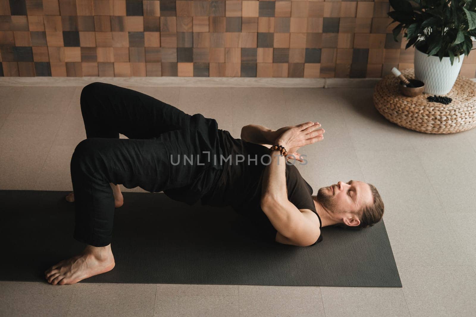 A man performing gymnastic exercises on a yoga mat at home by Lobachad