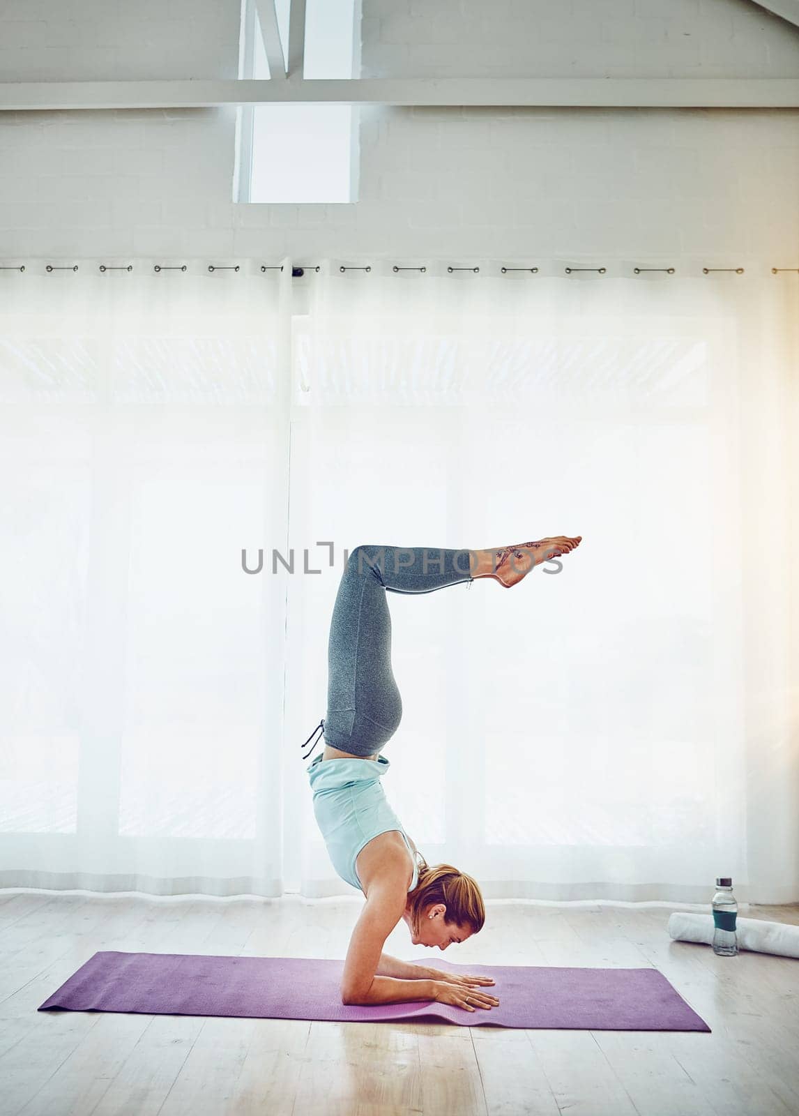 Yoga becomes a life practice not just an exercise routine. an attractive woman practising her yoga routine at home. by YuriArcurs