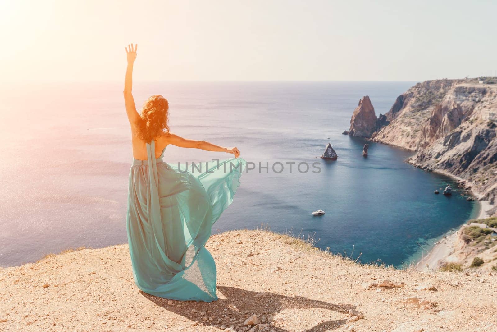 Side view a Young beautiful sensual woman with black hair in a long mint dress posing on a beach with calm sea bokeh lights on sunny day. Girl on the nature on blue sky background. Fashion photo by panophotograph