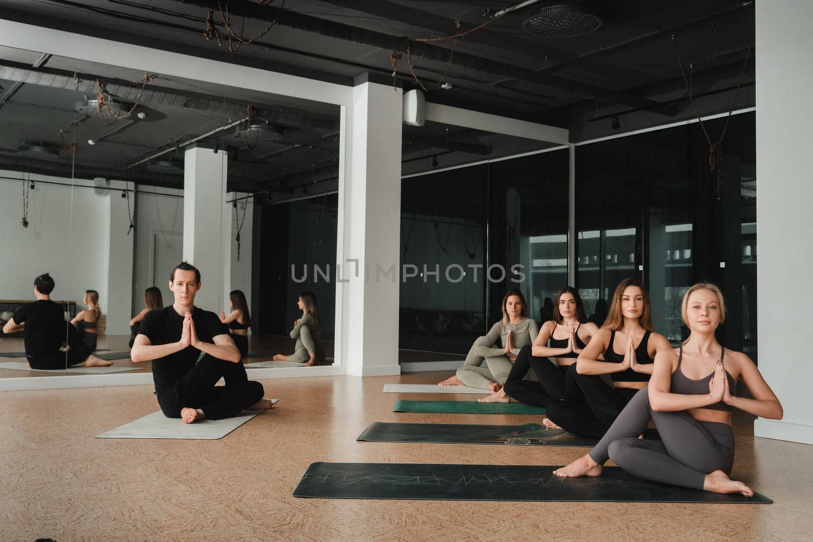 a group of girls do yoga in the gym under the guidance of a coach.