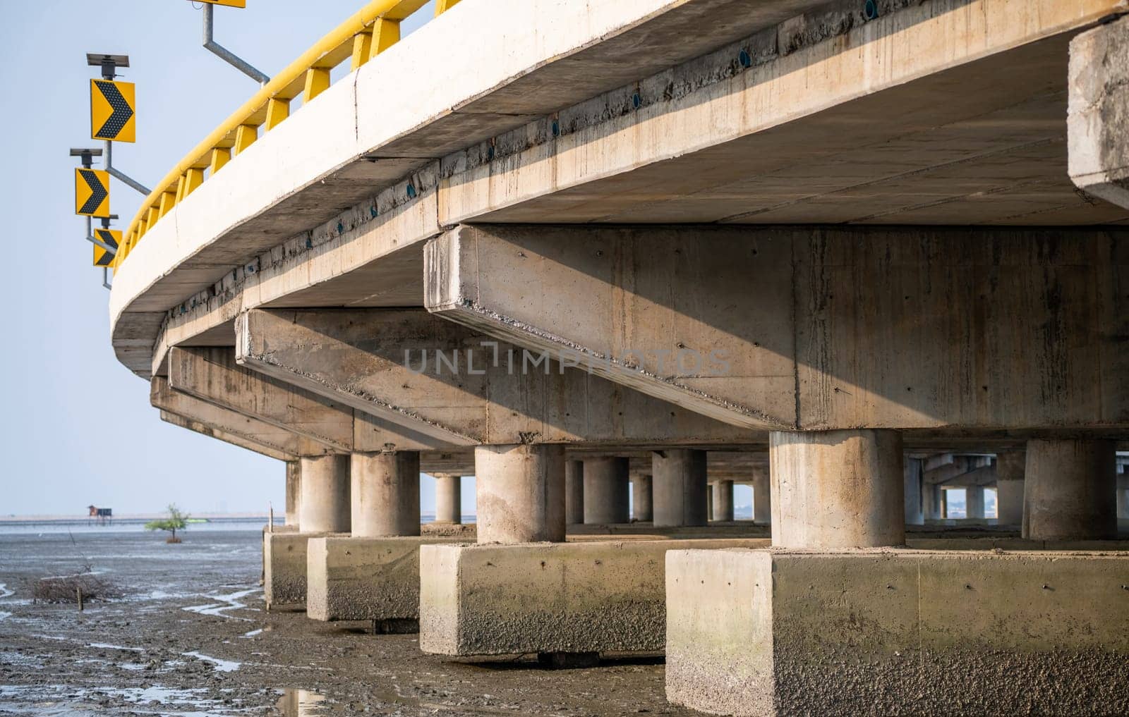Structure of reinforced concrete bridge along the sea. Bottom view of concrete bridge. Concrete bridge engineering construction. Modern cement bridge with strong column architecture. Infrastructure.