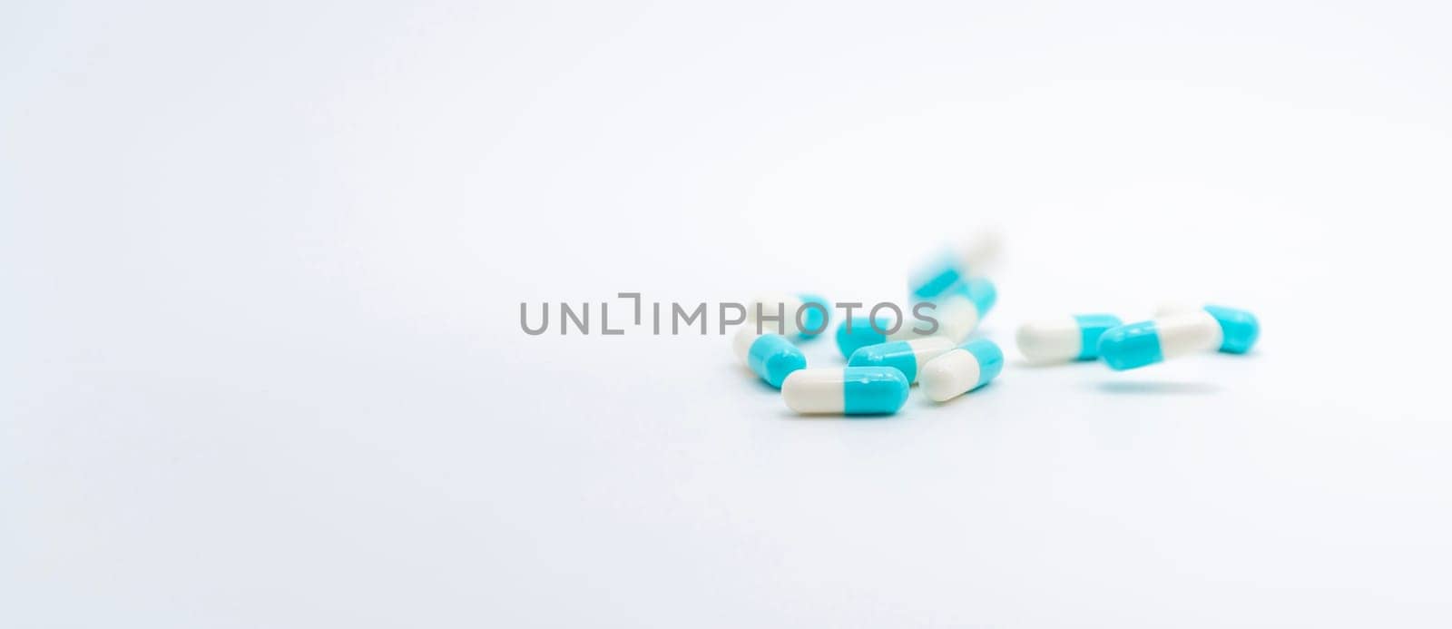 Antibiotic capsules pill falling on white background. Pharmacy banner. Antibiotic drug resistance. Prescription medicine. Medical healthcare concept. Pharmaceutical industry. Blue-white capsule pill.